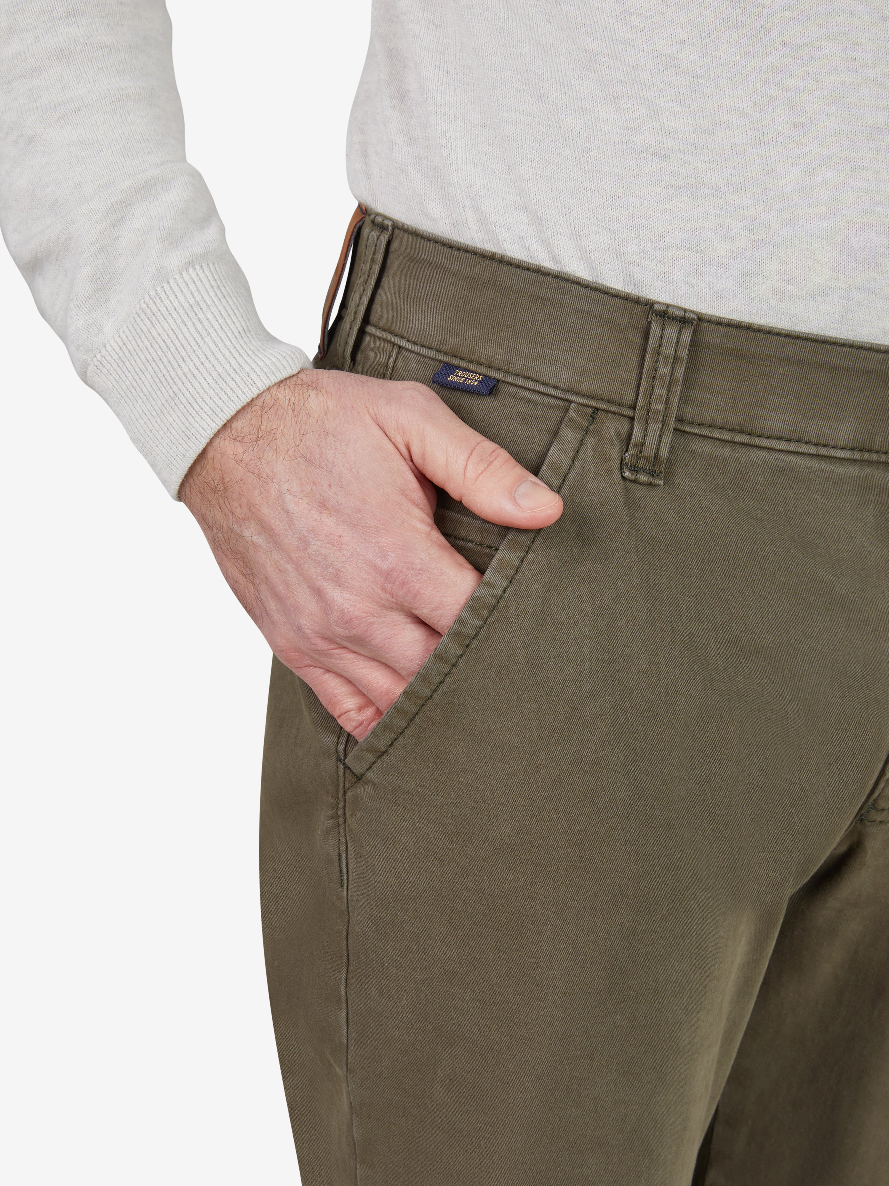 Nahaufnahme einer grünen Flat Front-Hose des Modells GARVEY 8070 von Club of Comfort, getragen von einer Person. Die Hose verfügt über einen elastischen Komfortbund, Hemdstopper, Münztasche, normale Leibhöhe und schmalere Beinverarbeitung. Hochwertiges Baumwollgewebe mit 360° Stretch und Safety-Pocket.