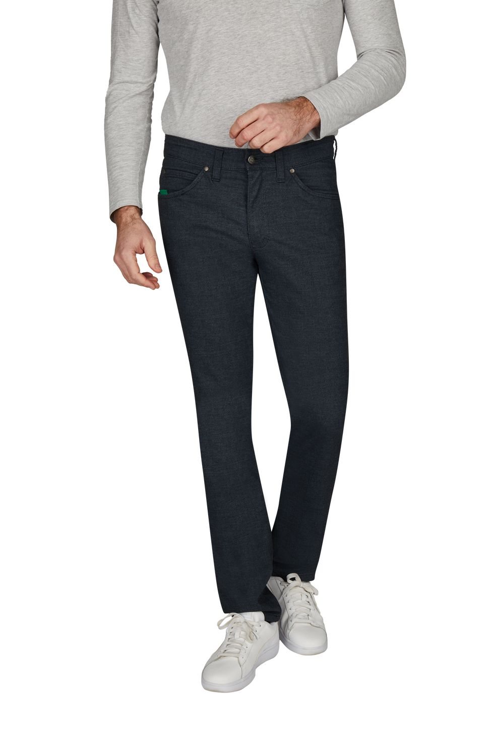 Ein Mann trägt dunkelblaue Jeans, ein hellgraues langärmeliges Oberteil und weiße Sneakers.