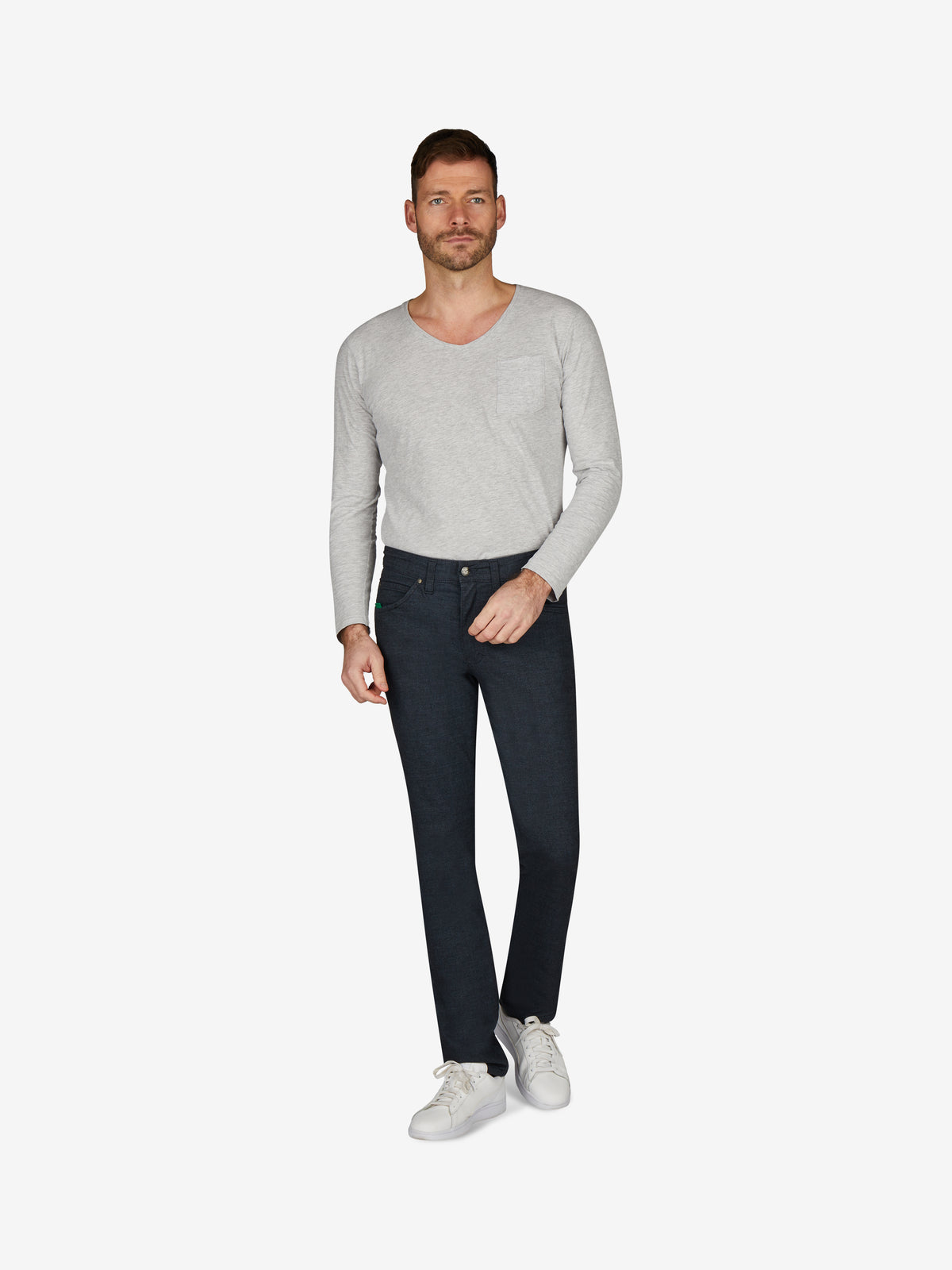 Mann trägt eine hellgraue Langarmbluse und dunkle Blau HENRY 7631 - marine melange 5-Pocket Jeans mit elastischem Komfortbund, Mobile Pocket in der rechten Vordertasche, Münztasche mit Kontrast-Patch, hergestellt aus Baumwoll-Wolloptik-Gemisch, für Herbst/Winter, regular Fit, schlankes Bein, auf weißem Hintergrund.