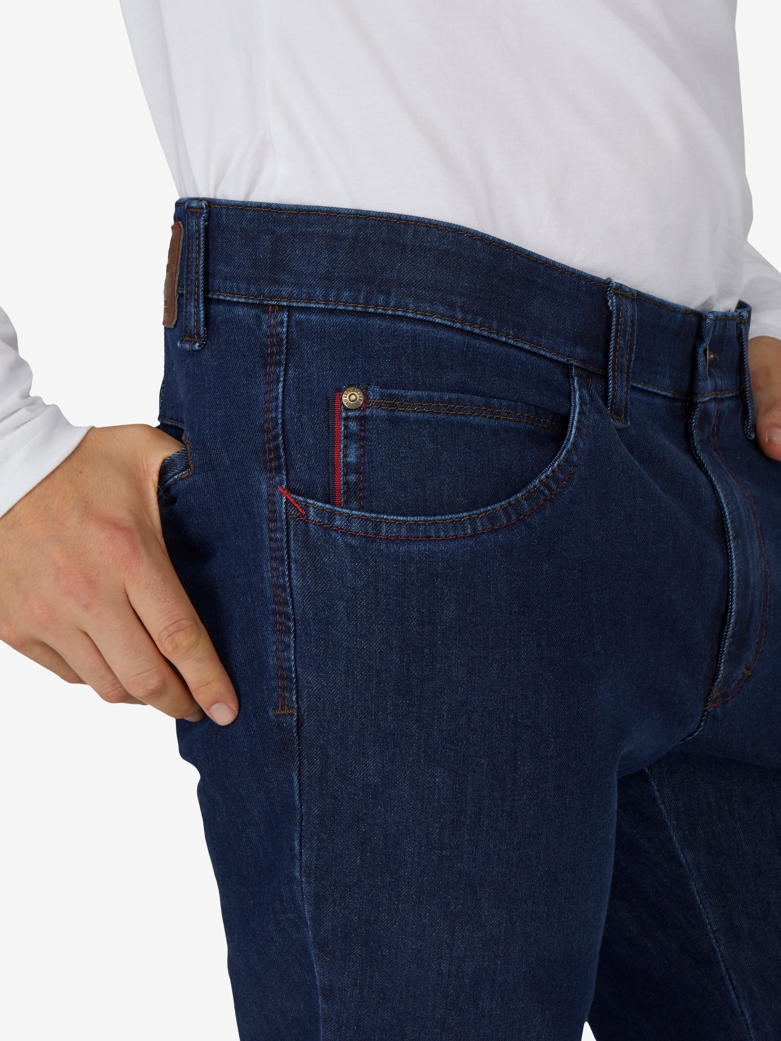 Nahaufnahme einer Person in jeansblauer Hose „MARVIN 7054“ von Club of Comfort, mit elastischem Komfortbund, Swing-Pocket, modifizierte 5-Pocket-Form, Regular Fit, aus hochelastischem Bi-Stretch-Denim mit T400-Beimischung, formstabil, kurz, ganzjährig, blaue Farbfamilie.