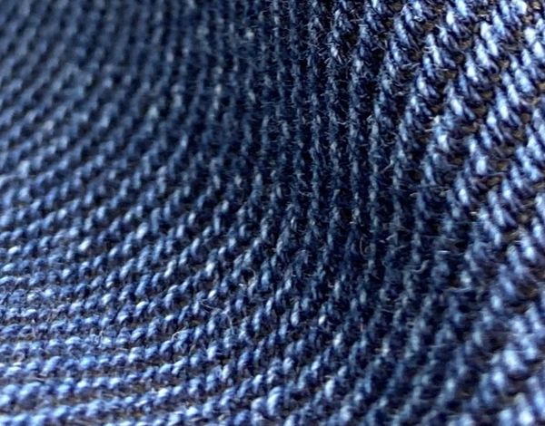 Nahaufnahme eines dunkelblauen, gestrickten Stoffes mit sichtbaren einzelnen Fäden und einer strukturierten Oberfläche.