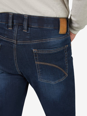 Nahaufnahme einer dunkelblauen, gewaschenen Flat Front-Hose mit elastischem Komfortbund, Hemdstopper und praktischer Bundverlängerung mit Knopf und Haken. Hergestellt aus hoch elastischem Super High-Stretch-Denim mit Lycra dual-FX®-Technologie. Die Hose hat eine normale Leibhöhe, eine großzügige Gesäß- und Oberschenkelweite sowie einen schmalen Beinverlauf.