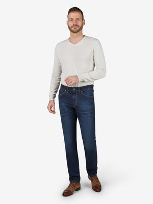 Mann trägt dunkelblaue, gewaschene ALEX 7915 Flat Front-Hose aus elastischem Super High Stretch-Denim mit Komfortbund, Hemdstopper und Bundverlängerung. Die Hose hat eine normale Leibhöhe, schmalen Beinverlauf, 6-Pocket-Design, geeignet für Ganzjahres und Figurtyp Regular.