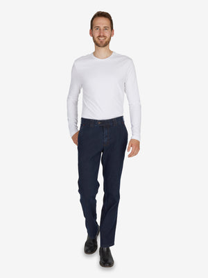 Mann trägt dunkelblaue DALLAS 4631 Jeanshose in straight Fit mit elastischem Komfortbund, Hemdenstopper, aus robustem Stretch-Ring-Denim, Shirt im weißen Langarm, lässiger Gesamtlook, Modellempfehlung für Ganzjahresgebrauch.