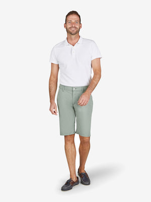 Mann trägt Weißes Polo-Shirt und hellgrüne Bermuda-Shorts mit elastischem Komfortbund, Hemdenstopper, High Stretch, aus Baumwoll-Tencel®-Mix, normaler Leibhöhe, Modell ESPANA 8109, Hersteller Club of Comfort, Frühling/Sommer, grüne Farbfamilie, modebewusst, bequem.