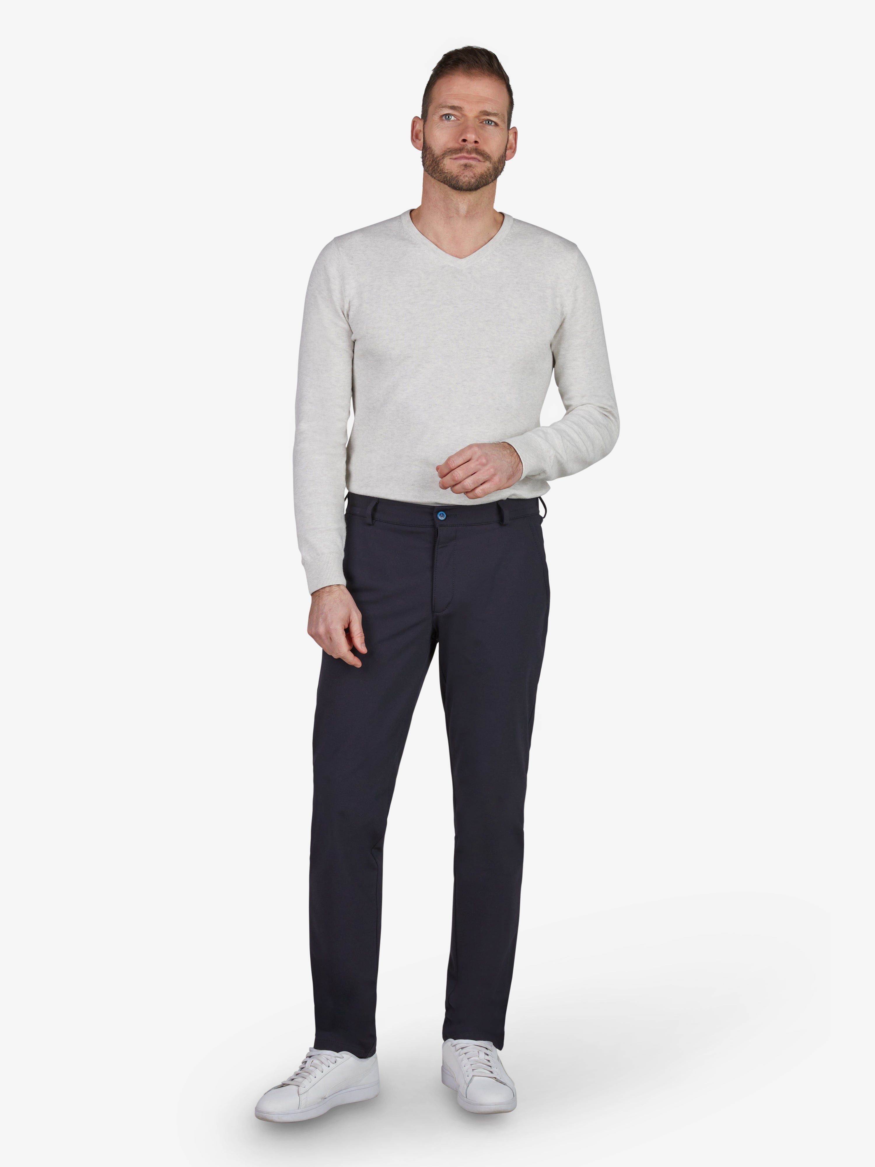 Männermodell trägt dunkelblaue FOXX 8240 Chinohose in Slim Fit mit elastischem Smokbund, Hemdstopper, mittlerer Leibhöhe, schmalem Bein, aus elastischem Polyamid-Viskose-Mix, Modell präsentiert in neutralem Stehpose, weißes Hemd, weiße Sneakers, Produktbeschreibung auf weißem Hintergrund.