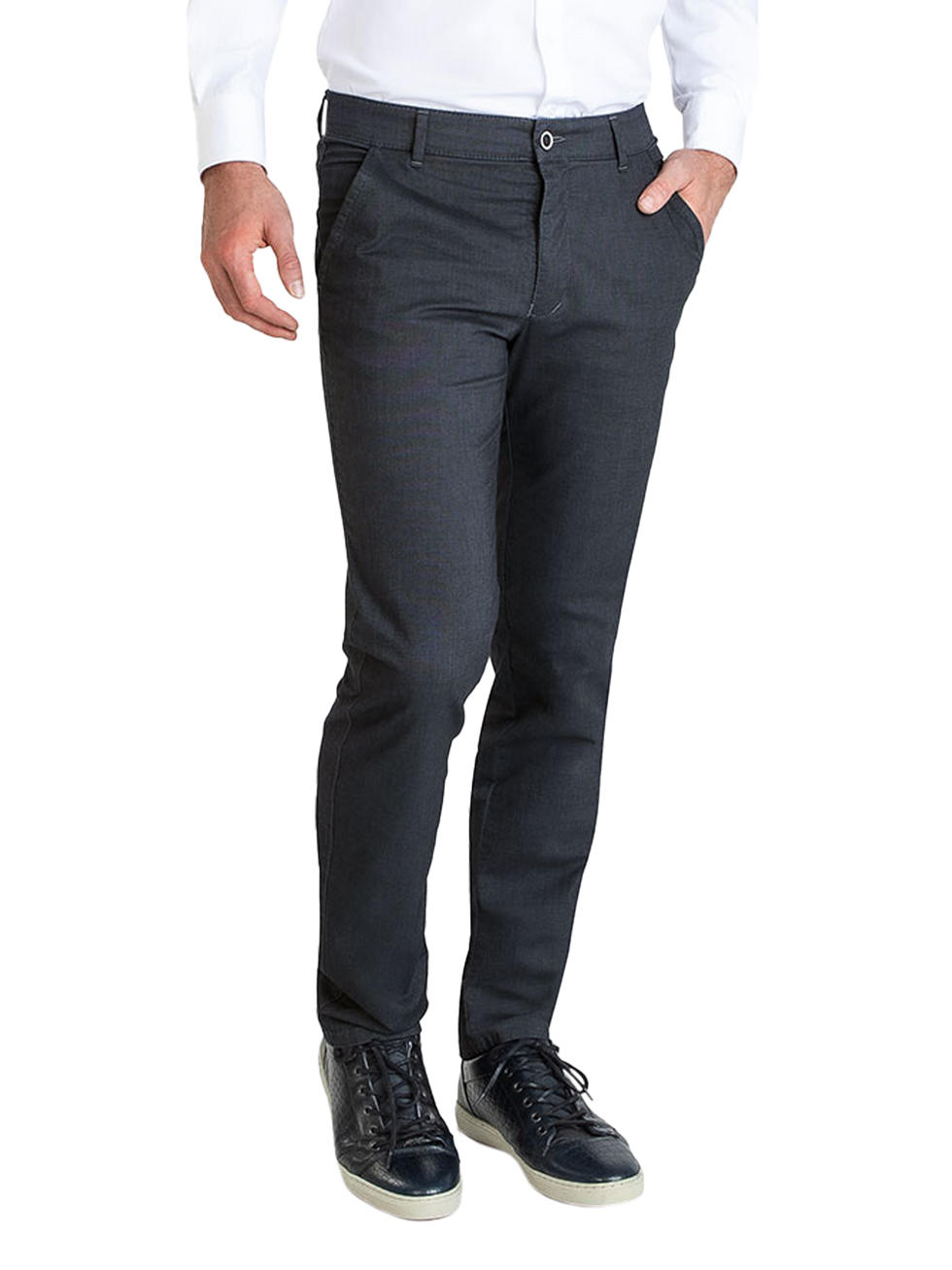 Ein Mann trägt eine weiße, langärmelige Hemd und dunkle, elegante Stoffhose mit Gürtel. Er hat eine Hand in der Hosentasche und trägt schwarze Sneakers.
