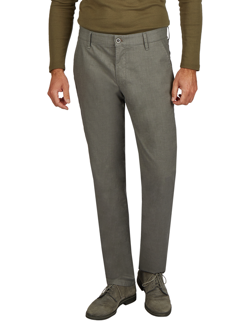 Blick auf eine Person, die graue Stoffhose trägt, die an der Taille mit einem Knopf und Reißverschluss geschlossen ist. Die Hose hat Gürtel-Schlaufen, und die Person trägt dazu braune Schuhe und ein grünes Oberteil.