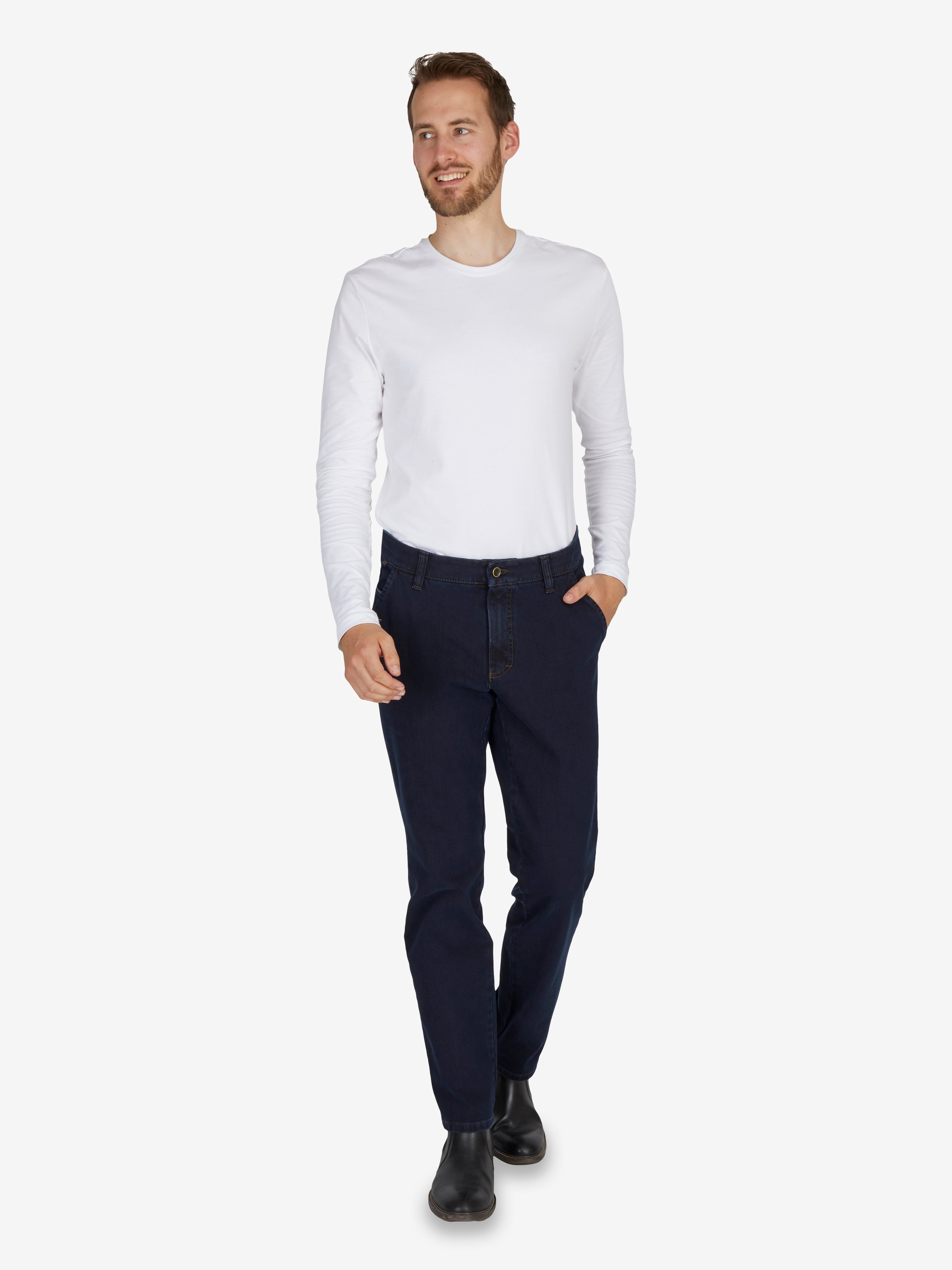 Ein Mann trägt eine dunkelblaue GARVEY 7054 Flat Front-Hose aus elastischem Bi-Stretch-Denim mit Komfortbund und Hemdstopper, kombinierte mit einem weißen Langarmshirt.