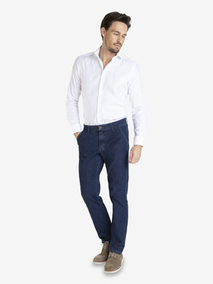 Mann trägt eine weiße Hemd und eine jeansblaue Flat Front-Hose GARVEY 7054 aus stretchigem Bi-Stretch-Denim mit elastischem Komfortbund, Hemdstopper, regulärer Leibhöhe und schmaler Fußweite.