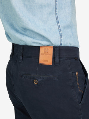 Nahaufnahme einer dunkelblauen Garvey 8070 Flat Front-Hose mit elastischem Komfortbund, Hemdstopper und Safety-Pocket, getragen von einem Model in hellblauem Hemd. Die Hose ist aus bi-elastischer Baumwolle gefertigt, hat eine normale Leibhöhe, schmalere Fußweite und ist für alle Jahreszeiten geeignet.