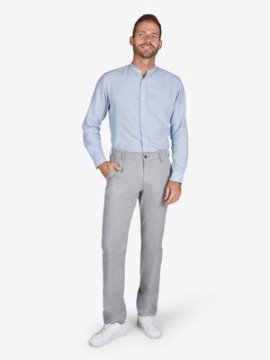 Mann trägt eine hellgraue GARVEY 8108 Flat Front-Hose mit elastischem Komfortbund und Hemdstopper, kombiniert mit einem hellblauen Hemd. Die Hose aus High Stretch Baumwoll-Mikrostruktur hat eine normale Leibhöhe, schmalere Fußweite und schlanken Beinverlauf, ideal für Frühjahr/Sommer.