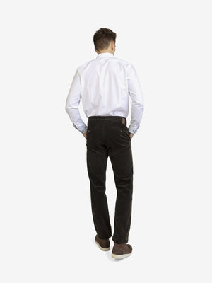 Mann trägt eine dunkelgrüne GARVEY 8200 Flat Front-Hose aus Feincord mit High Stretch, elastischem Komfortbund, Hemdenstopper und Bundverlängerung mit Knopf und Haken. Die Hose hat eine normale Leibhöhe, schmale Fußweite, perfekten Casual-Look und ist für Herbst/Winter geeignet.