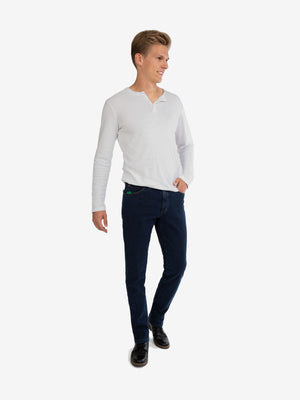 Herren in weißem Langarmshirt und dunklen Jeans, die HENRY 6822 - jeansblau aus High-Stretch-Denim mit Thermolite-Wärmeisolierung, Komfortbund mit Mobile Pocket, schmaler Beinverlauf, Regular Fit, Herbst/Winter.