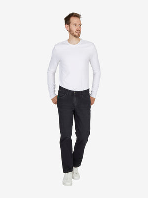 Mann in weißem Langarmshirt und schwarzen HENRY 7054 Jeans mit elastischem Bi-Stretch-Denim, 6-Pocket-Design, Mobile Pocket, Komfortbund, Regular Fit, schwarz, ganzjährig, model in Bewegung vor neutralem Hintergrund.