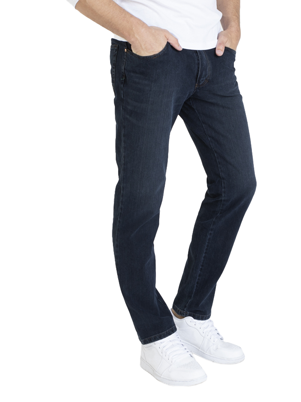 Ein Mann trägt dunkle Jeans, eine weiße T-Shirt und weiße Turnschuhe. Er hat seine Hände in den Taschen seiner Jeans und steht frontal.