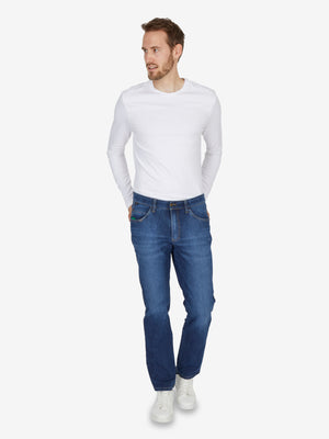 Mann trägt blaue, gewaschene Jeanshose "HENRY 7054" von Club of Comfort mit 6-Pocket, elastischem Doppelstoffbund, Hemdstopper und separater "Mobile Pocket" für Smartphone.