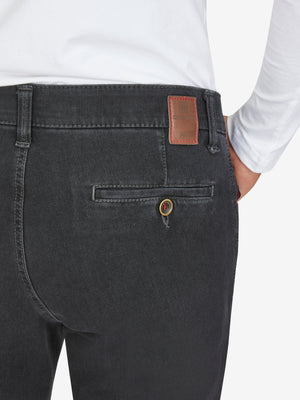 Nahaufnahme einer schwarzen Hose (MARVIN 7054 - anthrazit) von Club of Comfort, mit elastischem Comfortbund, Swing-Pocket, modifizierter 5-Pocket-Design, aus superelastischem Bi-Stretch-Denim, formstabil durch T400-Beimischung, normaler Leibhöhe, schlankem Bein, auf weißem Hemd getragen.