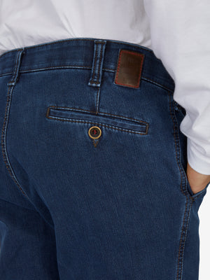 Nahaufnahme der GARVEY 6822 Jeansblau Flat Front-Hose aus High Stretch-Denim mit elastischem Komfortbund, Hemdstopper und Bundverlängerung mit Knopf und Haken, gefertigt aus Thermolite-Wärmeisolierung, Modell mit normaler Leibhöhe und schmaler Beinweite, getragen von einer Person in weißem Hemd.